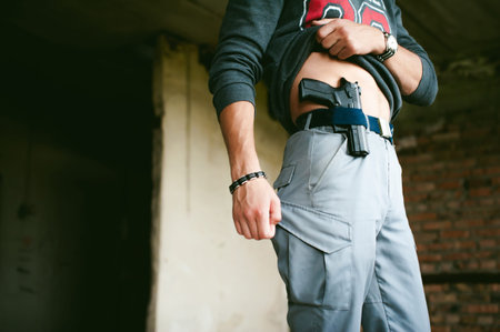 young athletic man holding a gun behind his belt.