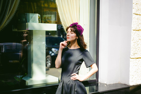 Beautiful woman in a dark stylish dress strolls along the street, near boutiques. Portrait of a fashionable girlの写真素材