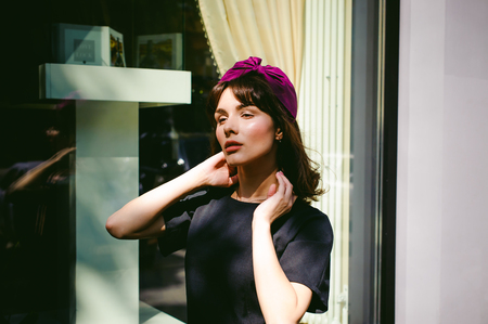 Beautiful woman in a dark stylish dress strolls along the street, near boutiques. Portrait of a fashionable girlの写真素材