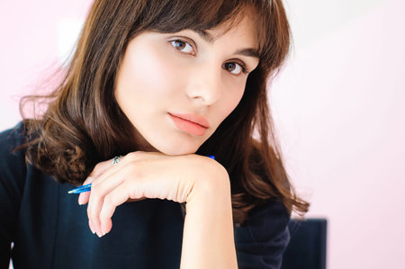 Portrait of a beautiful business woman making notes in a notebook. Holds a pen, sitting in the...