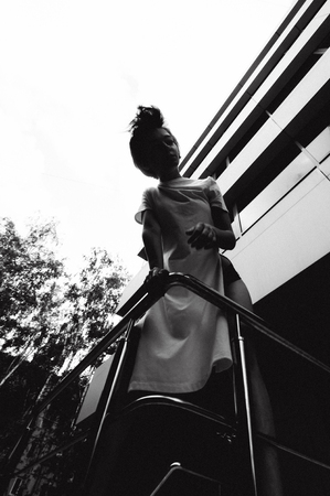 young woman with bare legs dressed in white sneakers and a long T-shirt, against the backdrop of cityscapes. street fashion, black and white styleの写真素材
