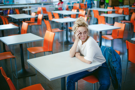 young beautiful woman in jeans clothes in business space of shopping center. portrait of a girl with freckles on her face, stylish girl in an empty cafeの写真素材