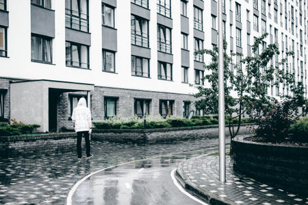 young man with beard in light checkered jacket with hood walking freely around city