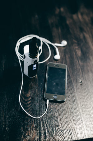 smartphone and electronic cigarette on a wooden table