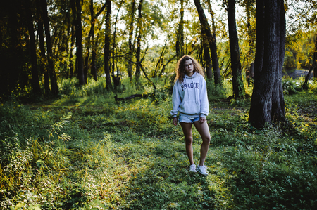 lovely young woman with curly hair, the romance of youth, a journey walk on a warm summer sunny dayの写真素材