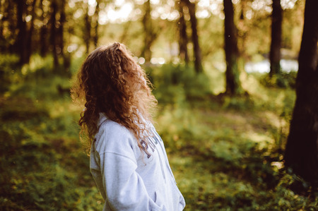 lovely young woman with curly hair, the romance of youth, a journey walk on a warm summer sunny dayの写真素材