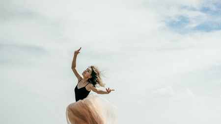 athletic woman stretching, jumping against the sky, a warm summer day, outdoor exerciseの写真素材
