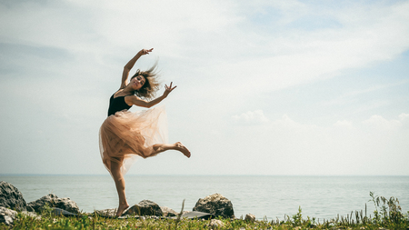 athletic woman stretching, jumping against the sky, a warm summer day, outdoor exerciseの写真素材