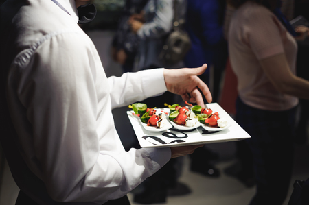 Waiter carrying trays with food. Caterring service for wedding, birthday or any company eventの写真素材