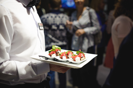 Waiter carrying trays with food. Caterring service for wedding, birthday or any company eventの写真素材