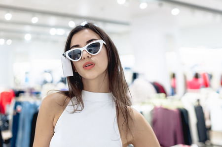 young beautiful emotional modern woman walks through the shopping center, looks at fashion things in clothing storesの写真素材