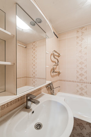 Interior of a modern bathroom with tiled walls and white bathtub