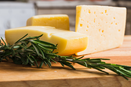 Russian cheese on a wooden board with seasoning razmarinの写真素材