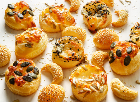 Cheese snacks with puff pastry sprinkled with a mix of seeds on a white backgroundの写真素材