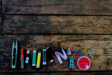 Scissors,thread and needles, striped fabric. Old sewing tools on the old wooden background. Vintage...