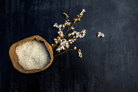 rice in sack,white rice in burlap sack with rice grain on the black woodの写真素材