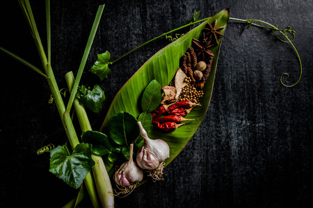 Herbs and spices around empty cutting board on dark stone background,cooking concept,Thailand.の写真素材