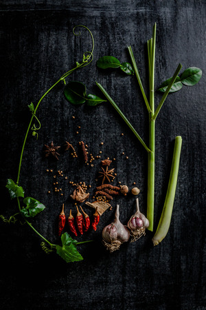 Herbs and spices around empty cutting board on dark stone background,cooking concept,Thailand.の写真素材