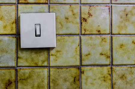 House electric light switch in ON position on aged old  yellow wall.の写真素材