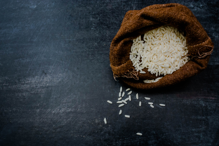 Thailand Rice on wooden table, rice in sackcloth and rice paddy on black wood,rice in sack,white rice in burlap sack with rice grain on the black woodの写真素材