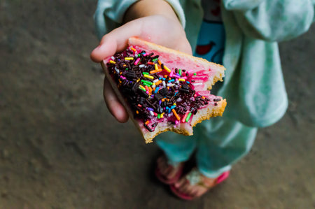 Baby holding a sandwich piece. The girl eat fast food, the baby is very hungry.