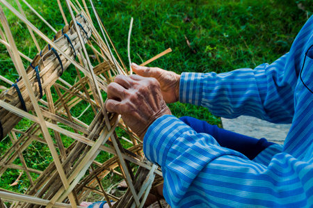 The basket-maker,Weave pattern hand bamboo, Bamboo weaving,Basket weaving , a village industry in thailand,Old Man's hands making a wicker basketの写真素材