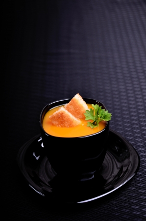 Orange soup in a black cupの写真素材