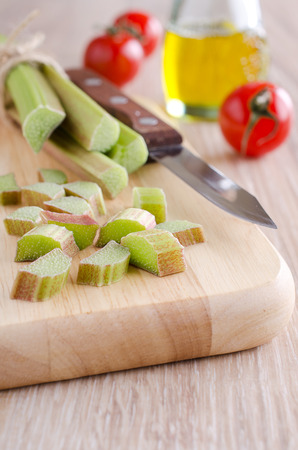 sliced ââwhole green rhubarb stalks lying on a wooden surfaceの写真素材