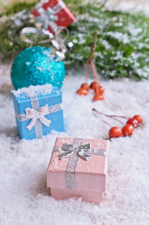 Christmas gifts and decorations on the white snow on the background of fir branchesの写真素材