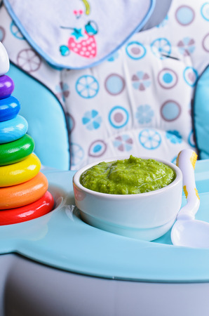 Puree of green in a small bowl stands on a childrens table for feedingの写真素材