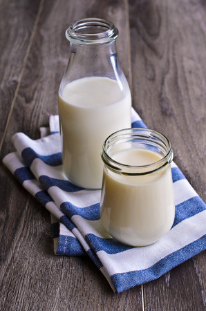 yogurt and milk in a glass container on striped clothの写真素材