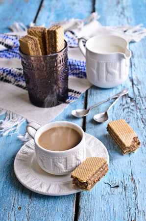 White mug of brown liquid on the old painted wooden boardsの写真素材