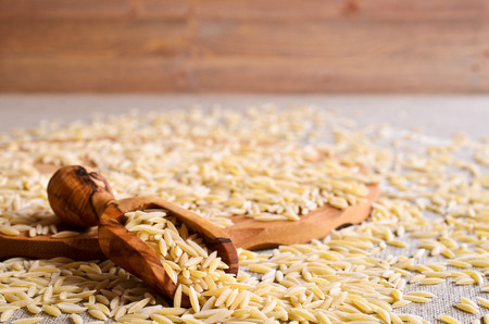 Pasta Orzo in the form of rice grains in a wooden scoopの写真素材