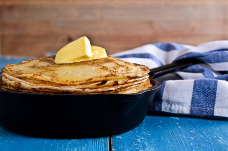 The stack of pancakes with butter on the background of the old wooden surfaces