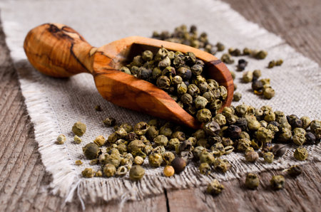 Green peppercorns in wooden scoop on burlapの写真素材