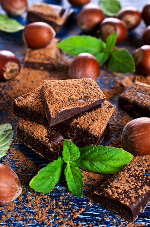 Chocolate, broken into pieces and sprinkled with cocoa powder with mint leaves and nutsの写真素材