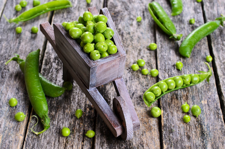 Fresh green peas in a drop of water on a wooden surfaceの写真素材