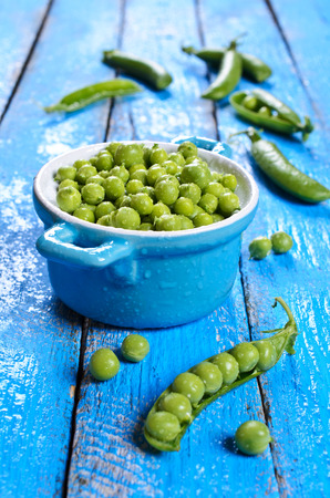 Fresh green peas in a drop of water on a wooden surfaceの写真素材