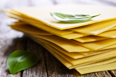 Sheets for lasagna with Basil leaves laid on a wooden surfaceの写真素材