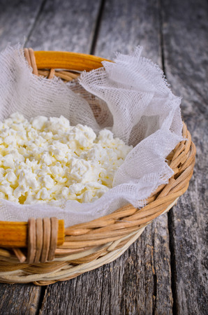 Cottage cheese in a wicker basket in rustic styleの写真素材