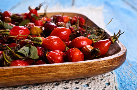 Rosehips in a wooden bowl on a wooden surfaceの写真素材