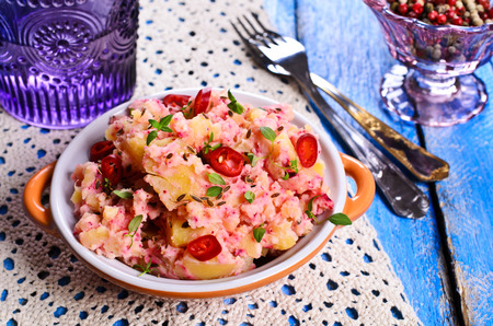 Potato salad with thyme and chili pepper in a ceramic dishの写真素材