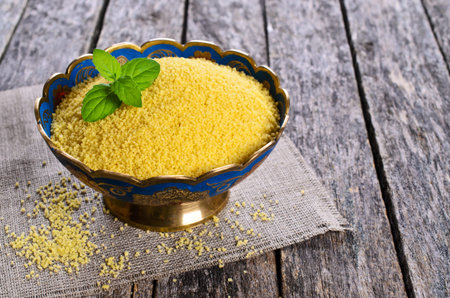 Couscous in a metal container on a wooden surface. Selective focus.の写真素材