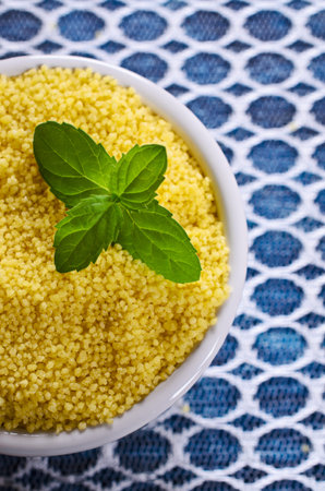 Couscous in a ceramic dish on a transparent cloth. Selective focus.の写真素材