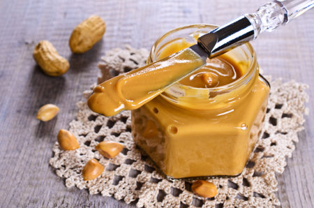 Peanut butter on the tip of the knife on the background of glassware. Selective focus.