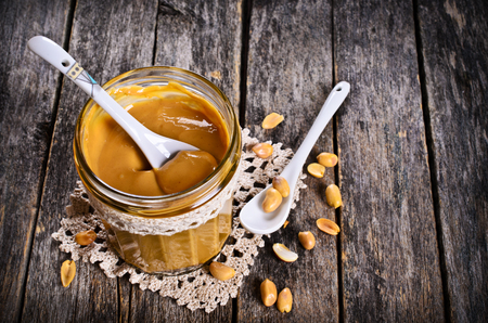 Peanut butter in a glass container on a wooden surface. Selective focus.の写真素材