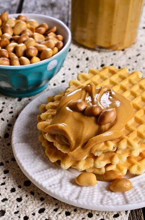 Waffles with peanut butter in a ceramic bowl on a wooden surface. Selective focus.の写真素材