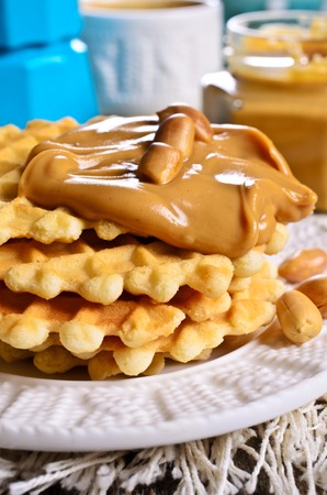 Waffles with peanut butter in a ceramic bowl on a wooden surface. Selective focus.の写真素材