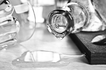 Neck of the bottle lying on the table surrounded by glassesの写真素材