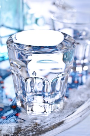 Bottles and glasses of clear liquid on a wet tableの写真素材